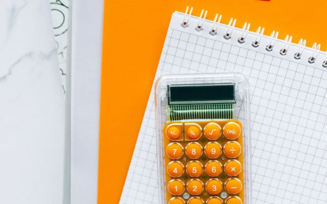 Calculator portocaliu pe un caiet cu pătrățele și un dosar portocaliu