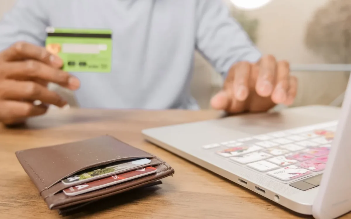 Mâini cu un card bancar lângă laptop