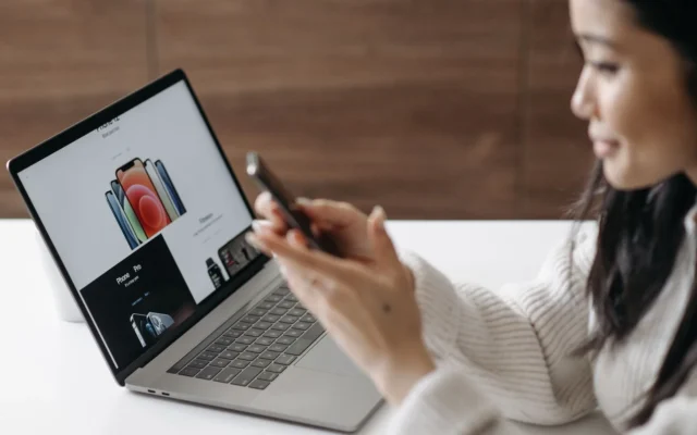 Persoană care folosește telefonul mobil lângă un laptop