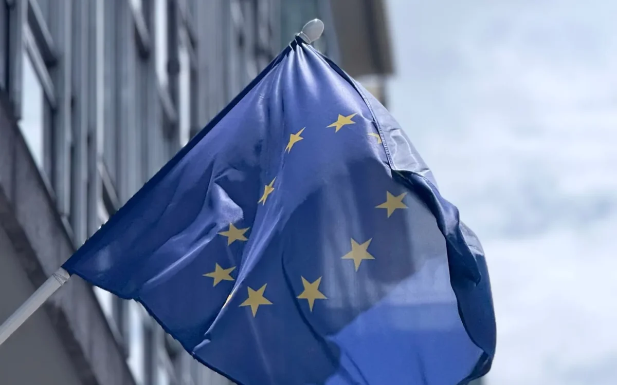 Drapelul Uniunii Europene flutură lângă fațada unei clădiri moderne