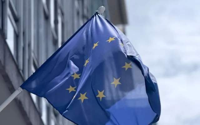Drapelul Uniunii Europene flutură lângă fațada unei clădiri moderne
