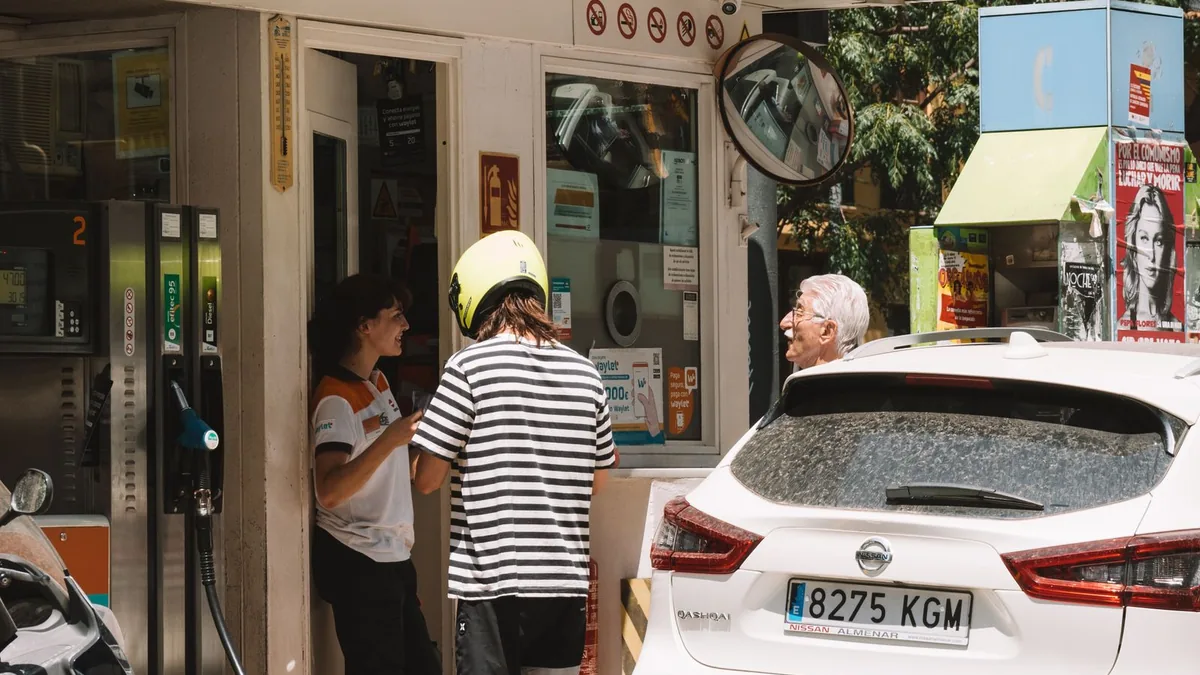 Autoturisme și persoane la o stație de alimentare