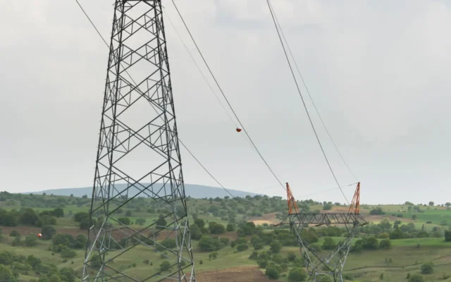 Doi stâlpi metalici ai unei linii electrice deasupra unor terenuri verzi